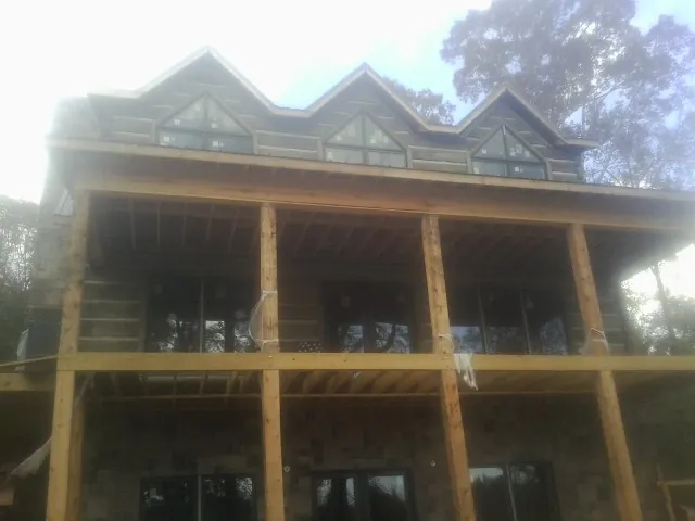 Dormers and porch framing on a large log home under construction — Roof Coating work by our crew in Clinton Township