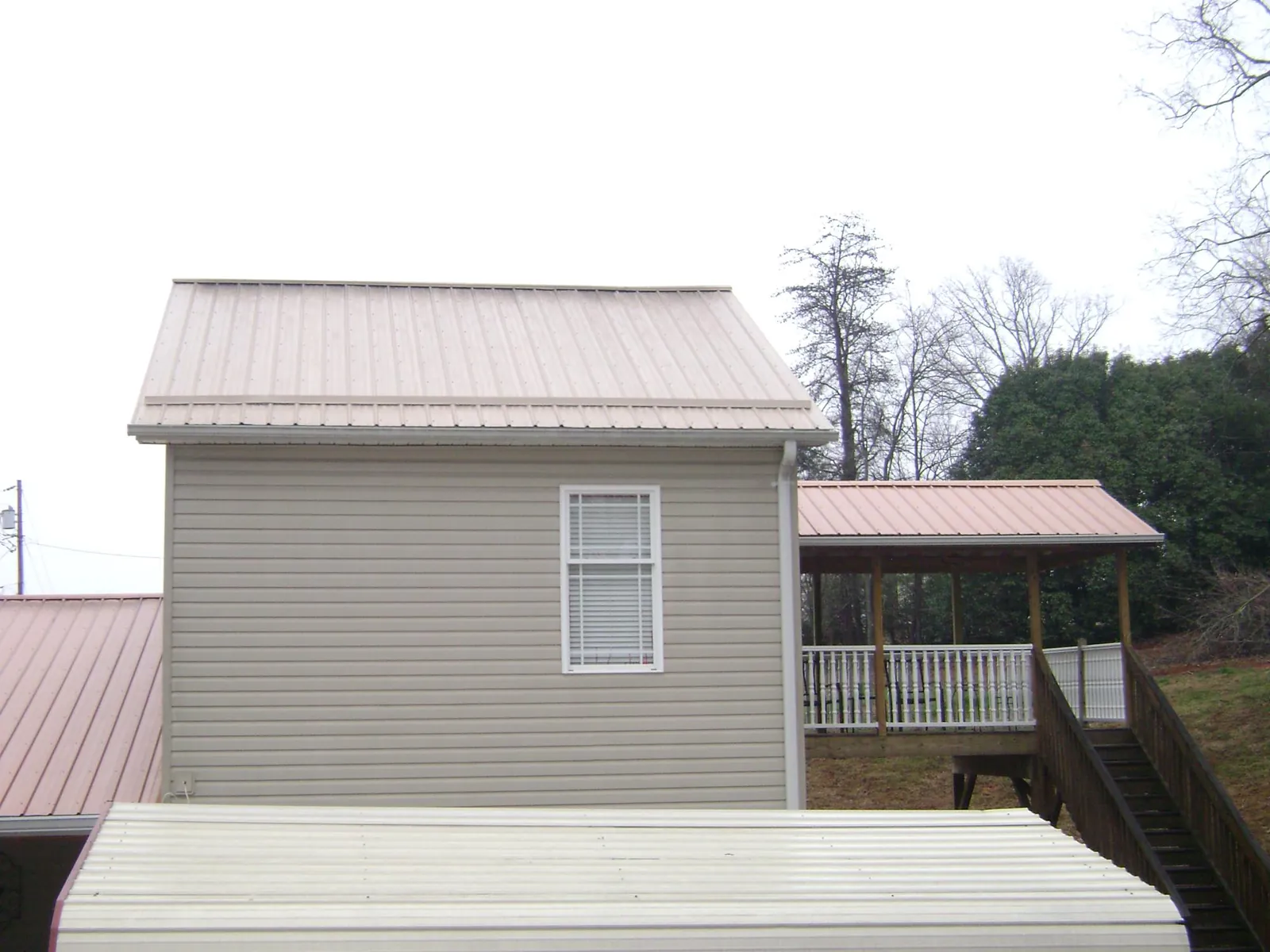 Tan metal roofs on a two story addition and attached porch, from a Roof Replacement job in Clinton Township
