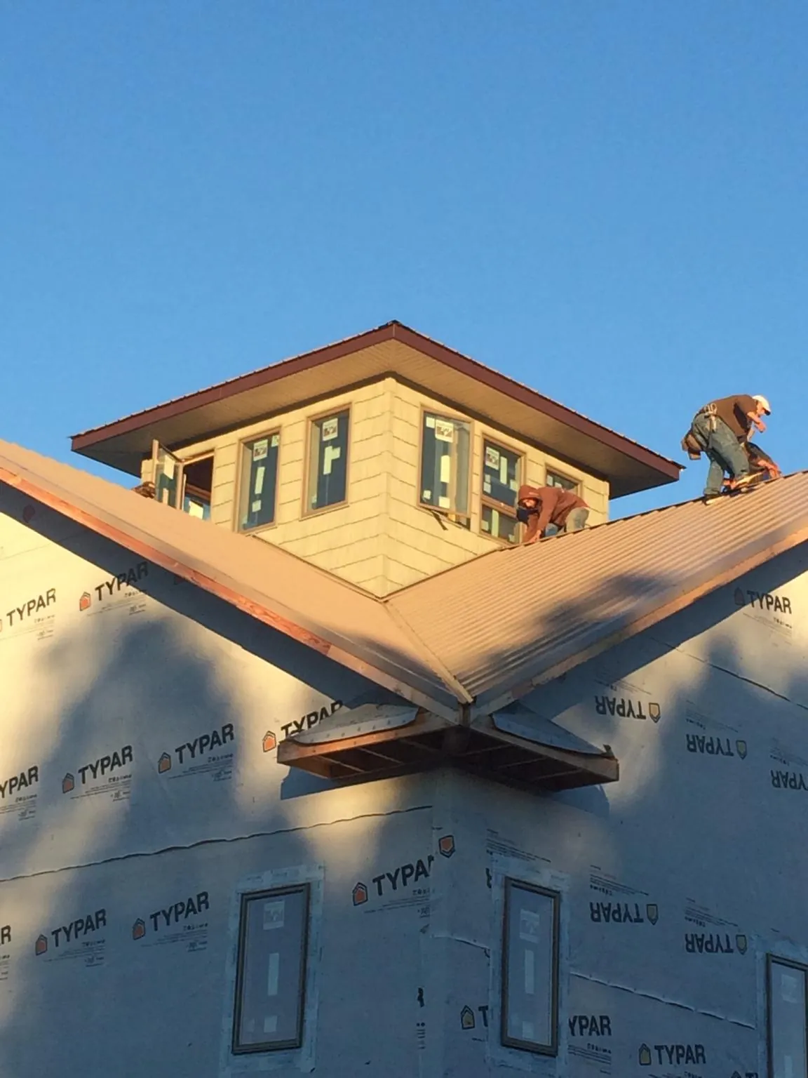 Roofers working around a rooftop cupola on a new metal roof at sunset — Roof Waterproofing in Clinton Township by Roofing Brothers